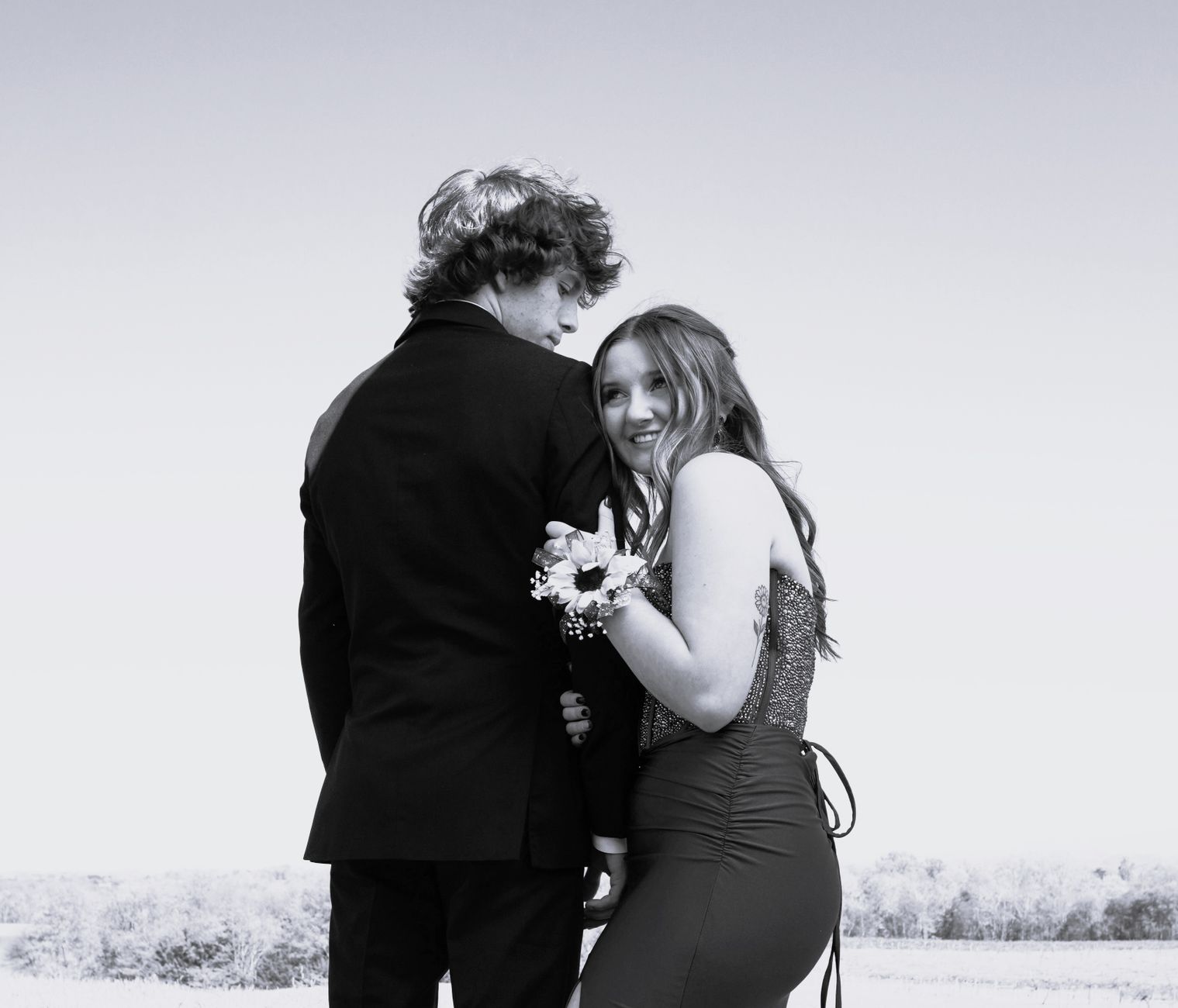 A black and white photo of a young couple in formal wear, with a corsage on the woman&rsquo;s wrist