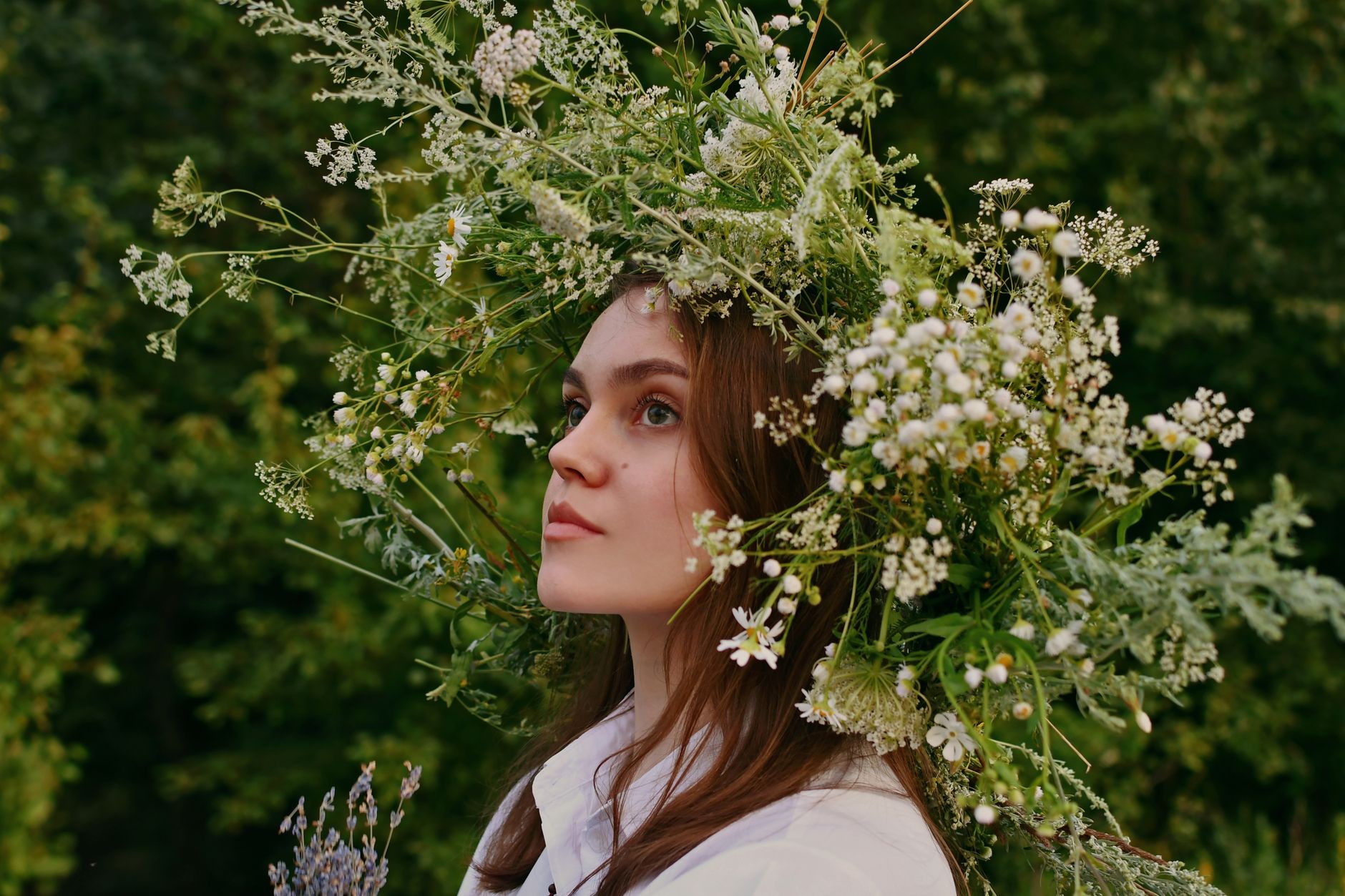 A woman wearing a dramatic wildflower and greenery crown made of queen anne's lace, daisies, and lavender